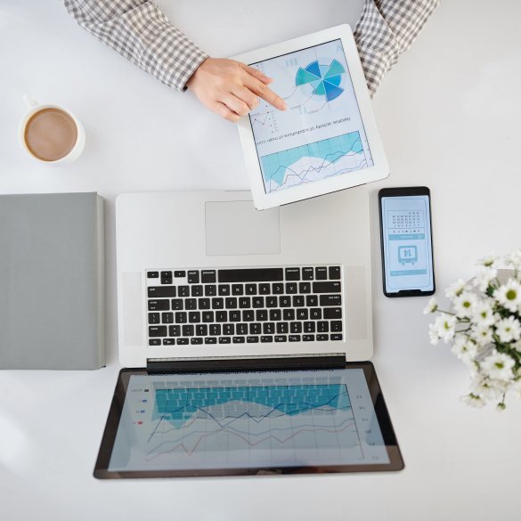 Businesswoman analyzing statistics in financial report on laptop and tablet computer and checking calendar on smartphone screen, view from the top